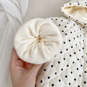 Close-up of baby winter jacket showing quilted polka dot fabric and warm fleece lining