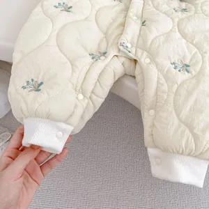 Close-up of diamond quilted fabric with floral embroidery and white snap button on baby romper