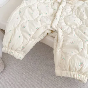Detail eines geblümten Baby-Stramplers mit Steppstoff, Spitzenkragen und Druckknöpfen