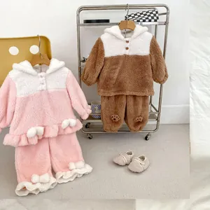Detail of plush coral fleece pajama sets with ruffled hems and cute pom-pom accents
