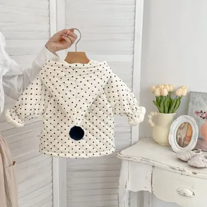 Detail of quilted baby hooded coat with polka dots, pompom decoration and fleece lining