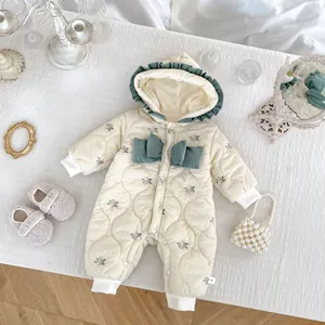 Detail of floral baby winter romper featuring green bows and embroidered quilted fabric