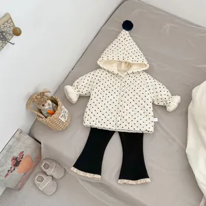 Detailed view of beige polka dot hooded jacket with pompom and lace-edged black pants
