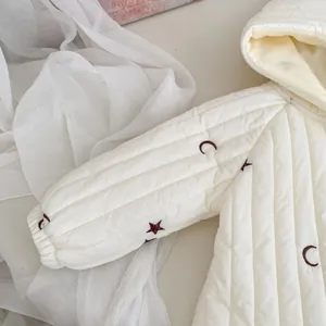 Detailaufnahme der weißen gesteppten Babyjacke mit brauner Stern- und Mondstickerei