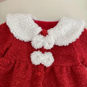 Détail du manteau d'hiver rouge pour bébé avec col en fourrure et nœuds blancs