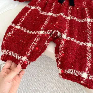 Détail d'une barboteuse bébé à carreaux rouges et blancs avec peluche et paillettes
