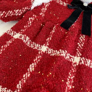 Détail d'une barboteuse bébé en tweed rouge avec sequins et nœud en velours noir