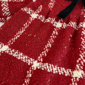 Close-up of red tweed fabric with gold sequins and a black velvet bow detail