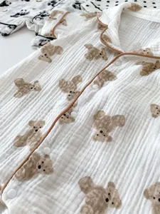 Detailed macro view of soft white cotton gauze baby romper with brown bear print