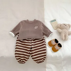 Détail à plat d'un sweat en polaire marron avec broderie ours et pantalon rayé