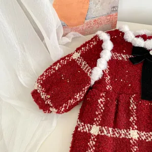 Détail d'un barboteuse rouge en tweed pour bébé avec fourrure et grand nœud en velours