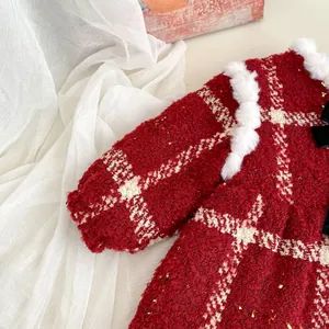 Close-up of red tweed girl dress with black bow, gold sequins and white faux fur trim