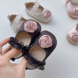 Dettaglio scarpe neonata in raso con rose di seta e cinturini in pizzo in tre tonalità