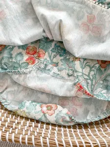 Nahaufnahme von Baby-Einteiler mit Blumendruck, Druckknöpfen und Spitzenbesatz-Details