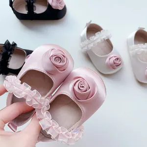 Dettaglio di scarpine in raso per neonata con rose 3D e cinturini in tulle arricciato
