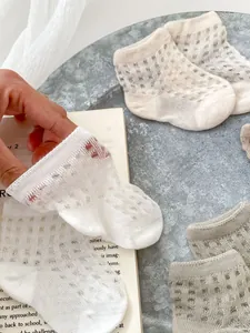Close-up of breathable mesh cotton baby socks in neutral tones with ribbed cuffs