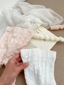 Close-up of baby mesh tights with delicate bow knots and breathable hollow knit texture