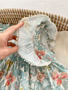 Detail eines geblümten Baby Mädchen Stramplers mit Rüschen und weißer Bommel-Borte