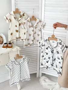 Close-up of cotton baby pajamas with bear prints hanging on a wooden hanger