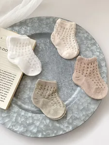 Detailed view of breathable mesh cotton baby socks in four natural earth tones on a tray