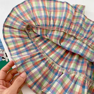 Close-up of rainbow plaid fabric showing detailed hem stitching and pleated texture