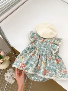 Detail eines geblümten Baby-Stramplers mit Spitzenbesatz, Pompons und Druckknöpfen