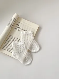 Close-up of white breathable mesh socks for babies with fine hollow knit details
