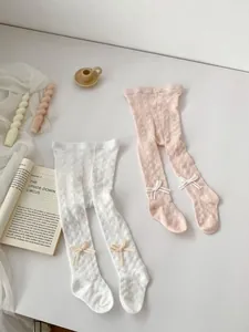 Close-up of baby mesh tights featuring hollow cable knit texture and cute ribbon bows