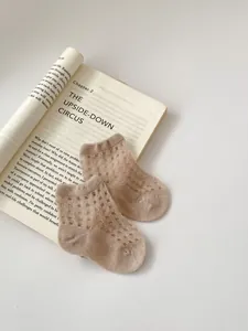 Detail of breathable mesh knit and elastic ribbed cuff on soft beige cotton baby socks
