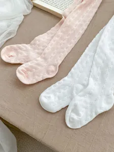 Close-up of pink and white baby tights featuring breathable hollow-out wave knit patterns