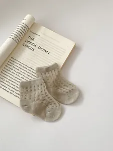 Detail view of thin breathable mesh cotton baby socks on a book for summer wear