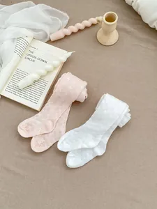 Close-up of pink and white baby tights with delicate hollow knit texture on fabric