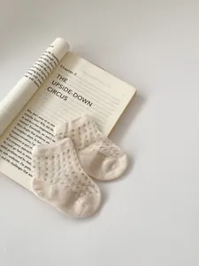 Detailed macro view of cream-colored mesh knit baby socks with breathable cotton fabric