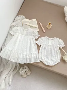 Flat lay of white floral lace baby bodysuit and dress set with elegant vintage details