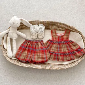 Flat lay of baby girl plaid ruffle top and bloomers with lace shoes in a basket