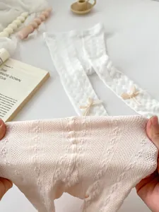 Detail of breathable lace knit texture and yellow bow on toddler white leggings