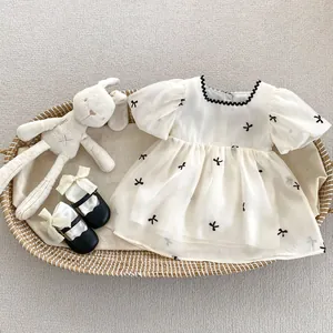 Witte babyjurk met pofmouwen en zwarte strikborduurwerk inclusief babyschoentjes