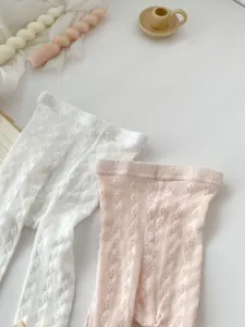 Detail of white and pink infant mesh tights with hollow jacquard patterns and elastic waist