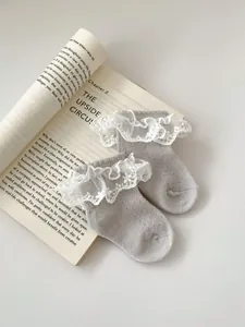 Close-up of baby girl lace socks with white embroidery on vintage book background