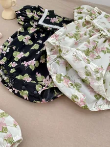 Detail of floral baby rompers featuring lace trim and ruffled collar on knit background