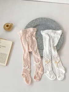 Detailed close-up of baby girl mesh tights with hollow knit patterns and bow knots
