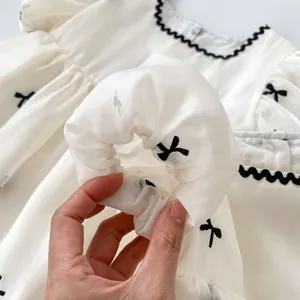 Detail van baby zomerjurk met zwart strikborduursel en golvende ruches aan de rand
