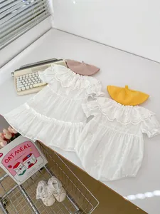 Detailansicht eines weißen Baby-Spitzenkleides und Stramplers mit Vintage-Stickerei