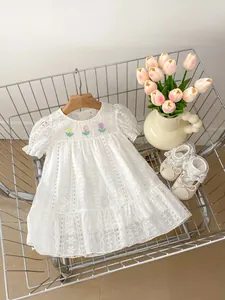 Detailed close-up of white lace dress with floral embroidery and ruffle trim in a cart