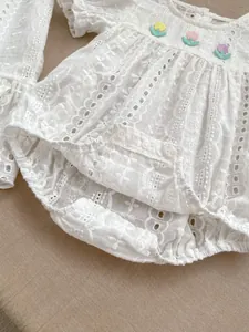 Close-up of white baby lace romper with floral embroidery and ruffle sleeve details