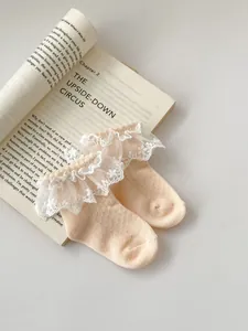 Close-up of baby girl socks featuring delicate white lace trim and soft cotton mesh fabric