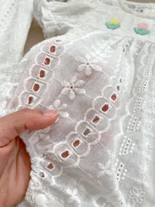 Detail of baby cotton jumpsuit featuring delicate floral lace and tulip embroidery
