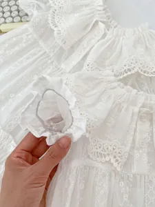 Nahaufnahme von weißem Sommerkleid mit floraler Stickerei und Spitzenrüschen