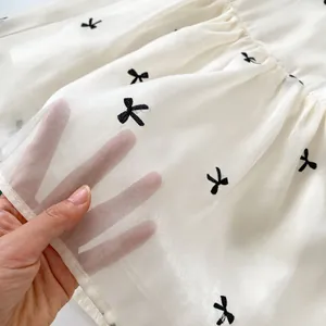 Doorschijnende witte babyjurk met zwarte strikborduurwerk en pofmouwen materiaal