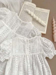 Detailed view of white floral eyelet embroidery and small buttons on cotton baby romper